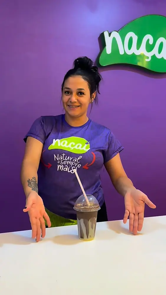 Atendente do Naçaí sorrindo com um milk shake no balcão