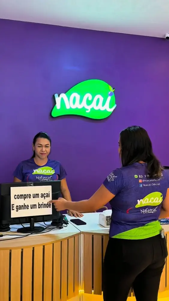 Balcão da loja Naçaí com o logo em neon e a equipe atendendo